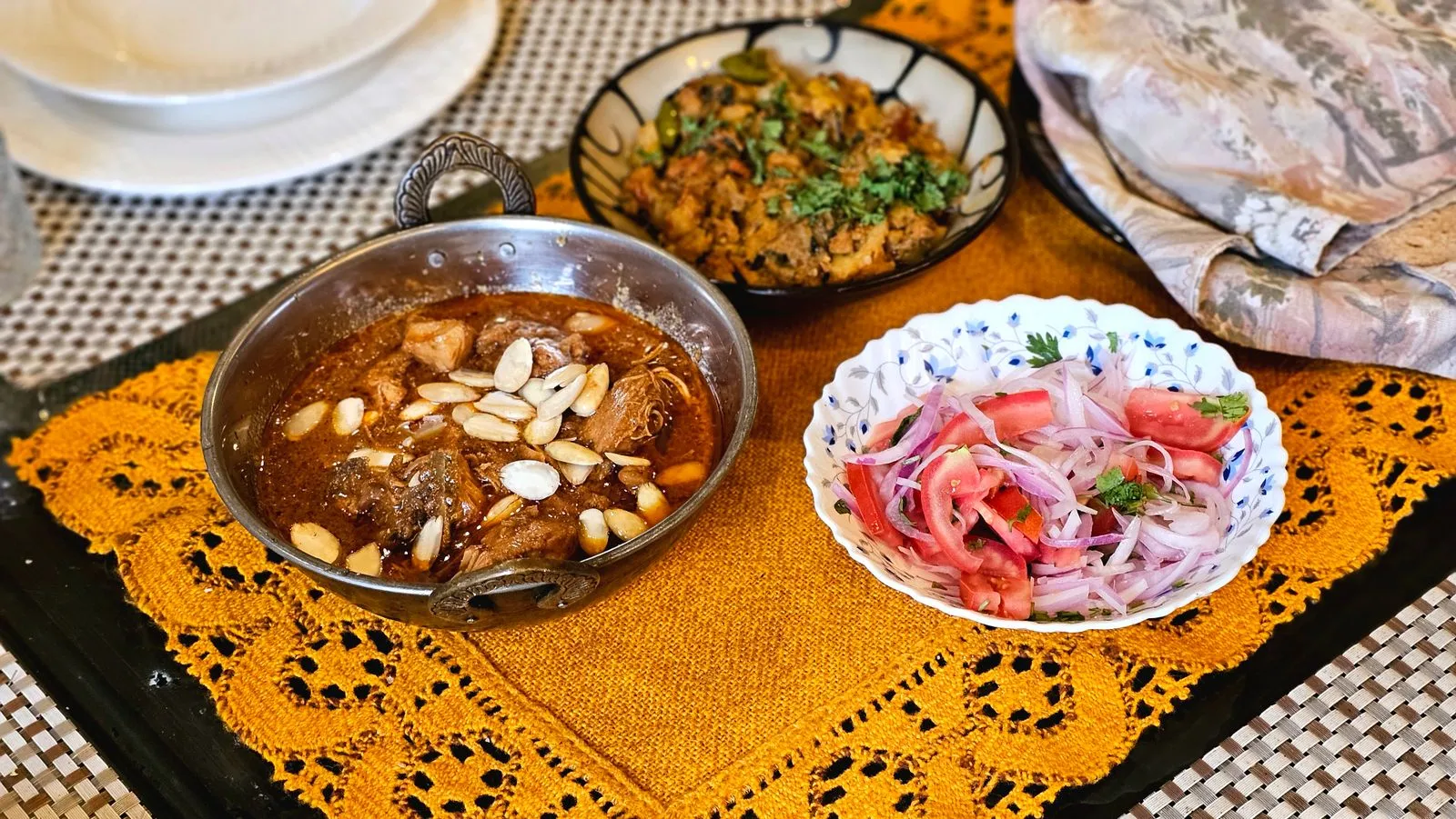 Delicious Indian meal featuring a hearty curry with almonds and fresh salad on a decorative mat.